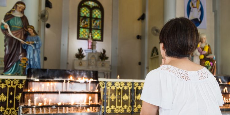 Believer kneel and praying in a Catholic church