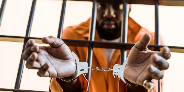 they are hid in prison houses kjv - african-american-prisoner-in-handcuffs